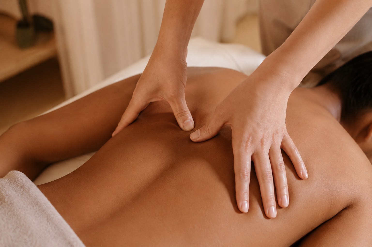 Therapist applying firm thumb pressure to a client's back during a remedial massage treatment